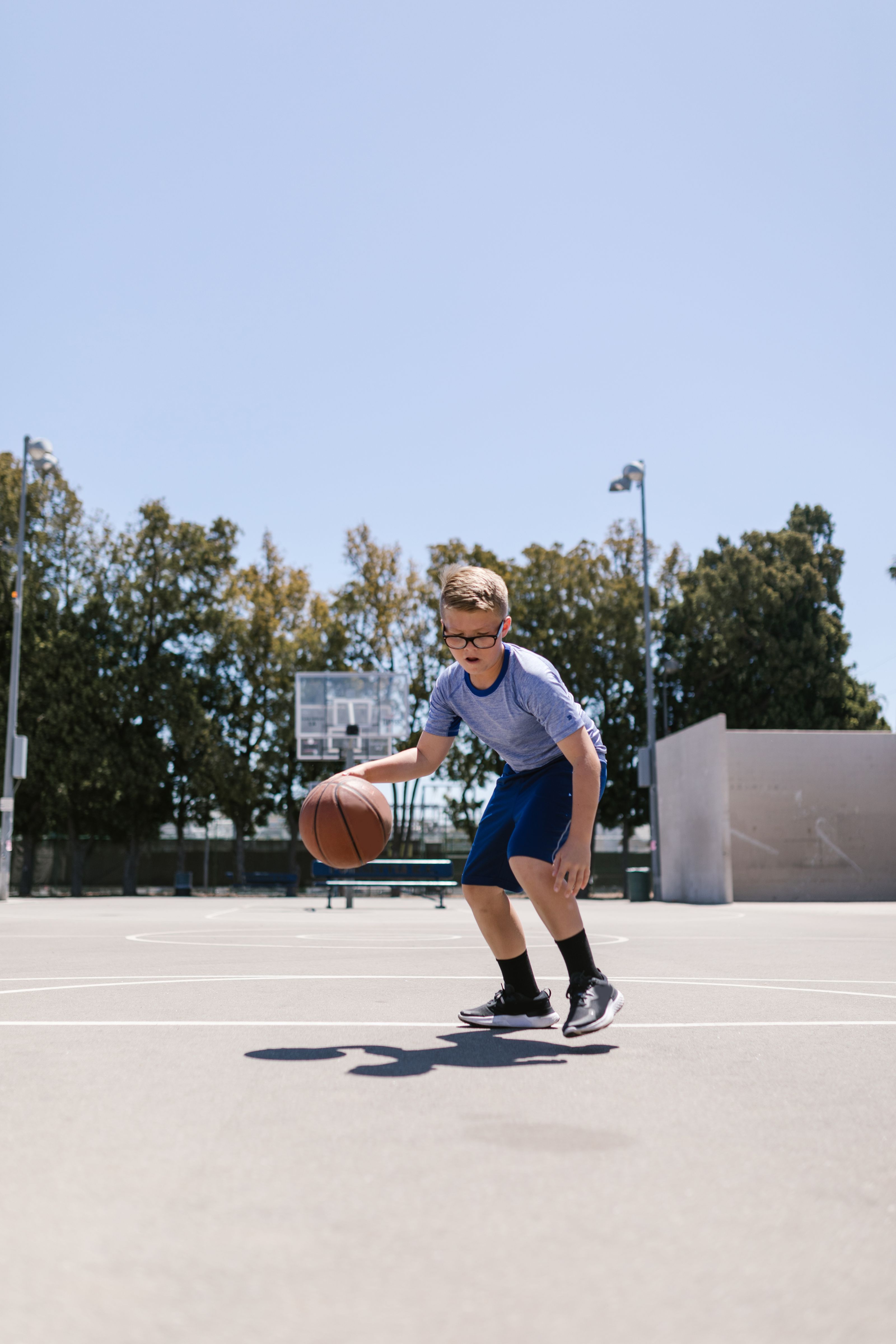 Young child dribbling a basketball on a sunny outdoor court
