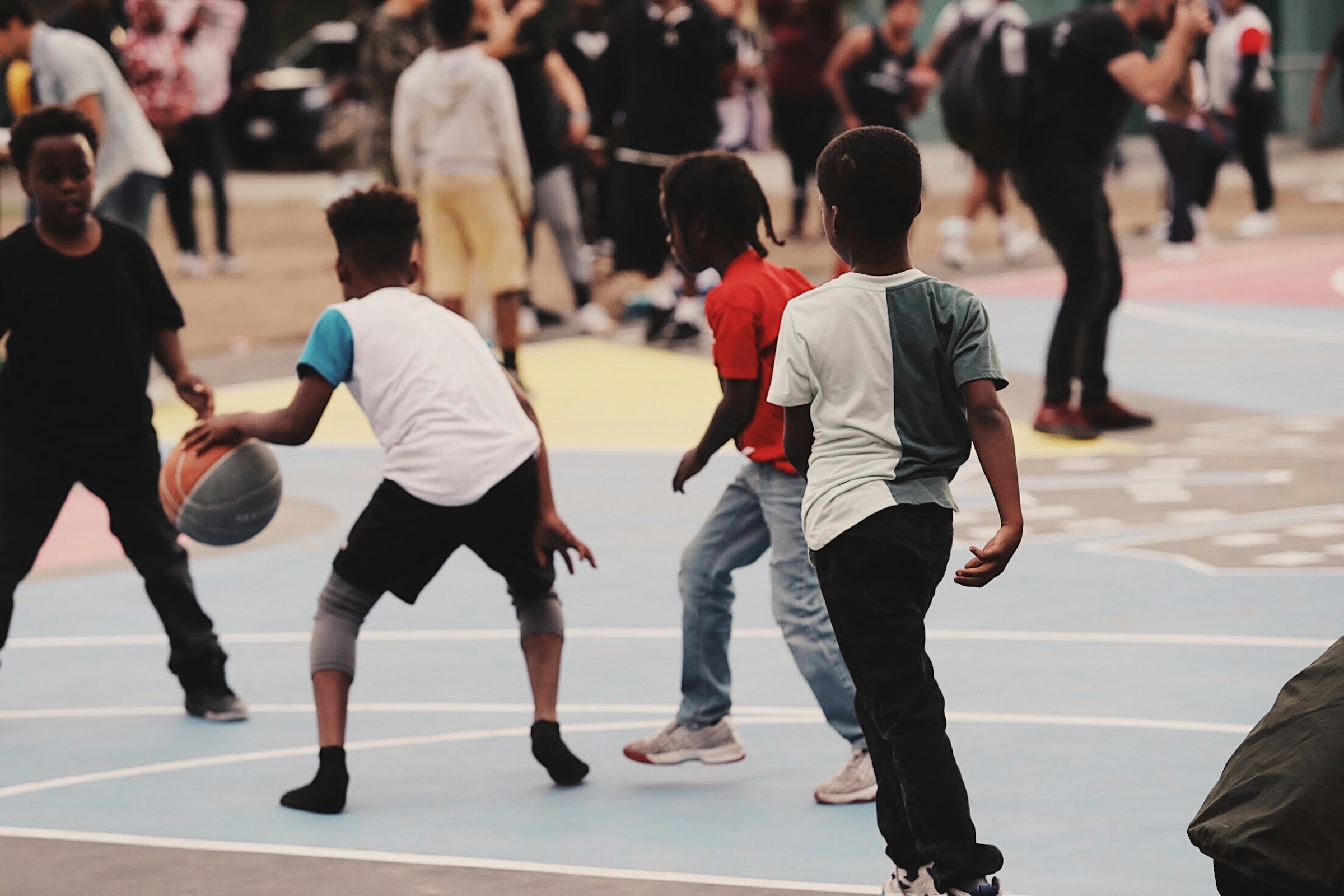 Kids playing basketball together on an outdoor court